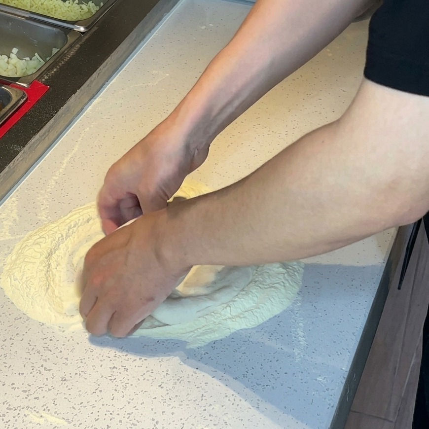 손바닥을 사용하여 반죽을 밖으로 펴고 늘리는 모습.
