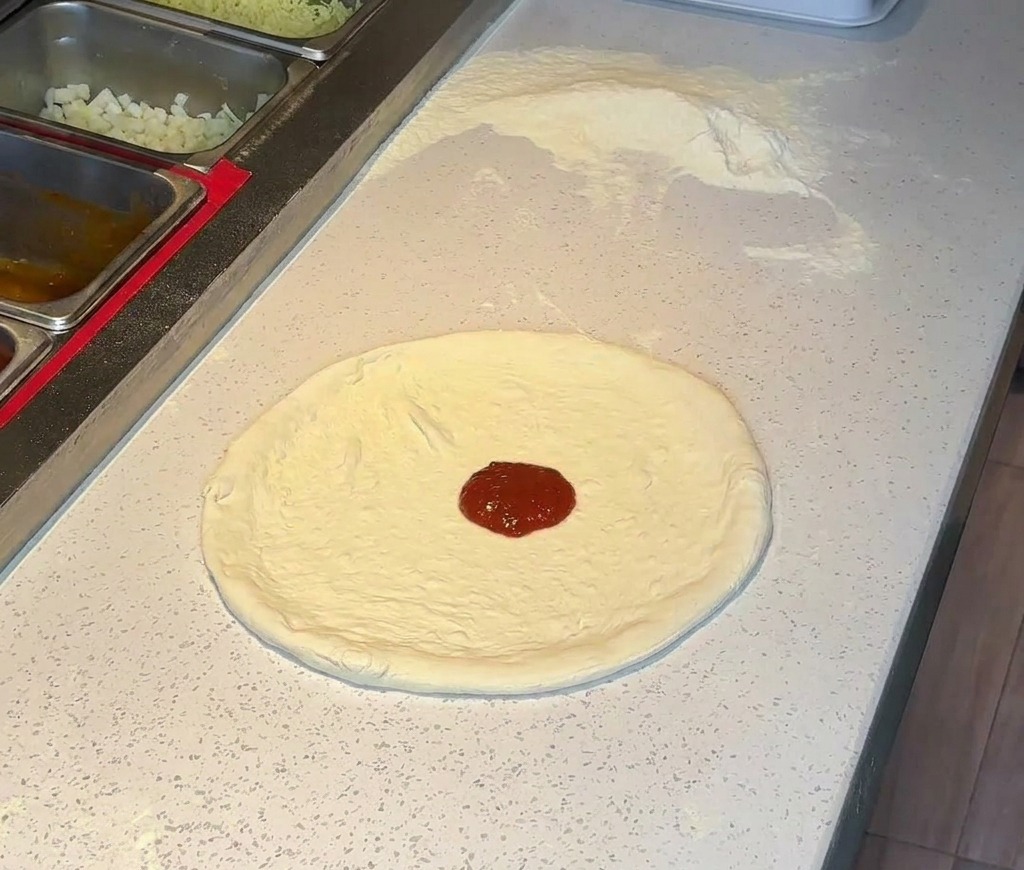 늘려둔 도우 중앙에 토마토 소스를 올리는 모습.