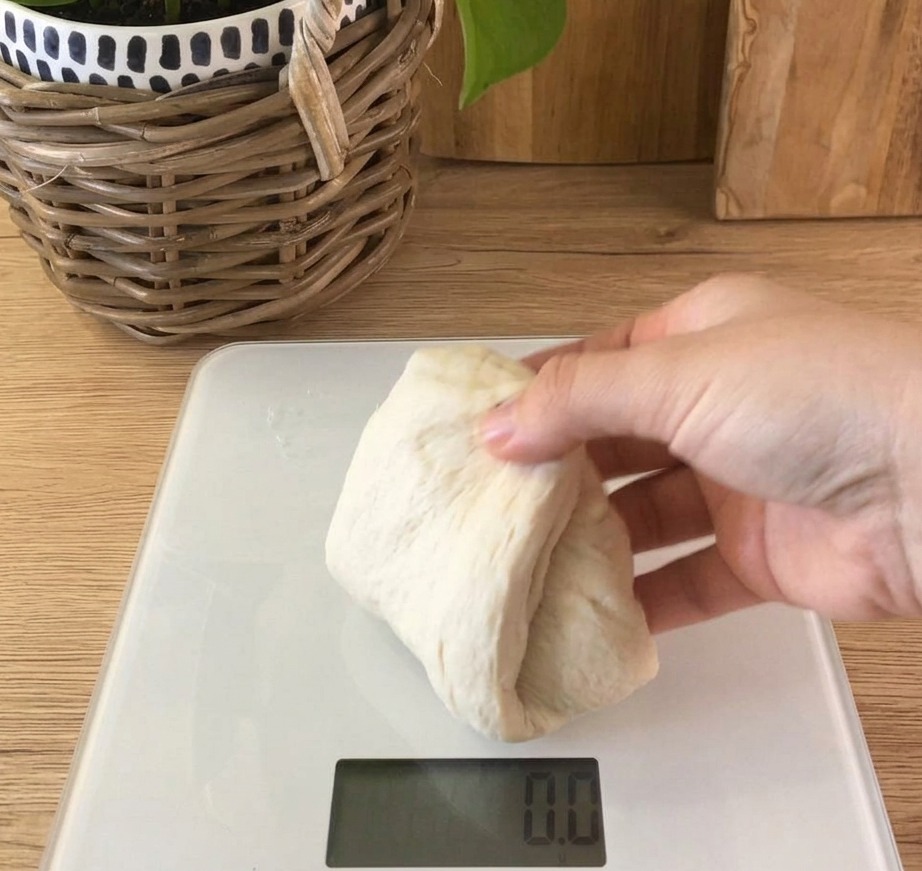 주방용 저울 위에 100g씩 분할된 부드러운 빵 반죽이 놓여 있는 모습.
