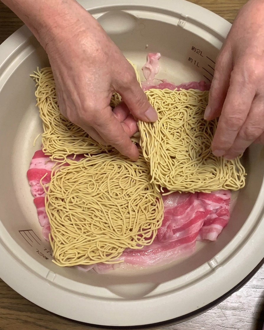 냄비 안 삼겹살 위에 라멘 면 블록을 올리는 모습.