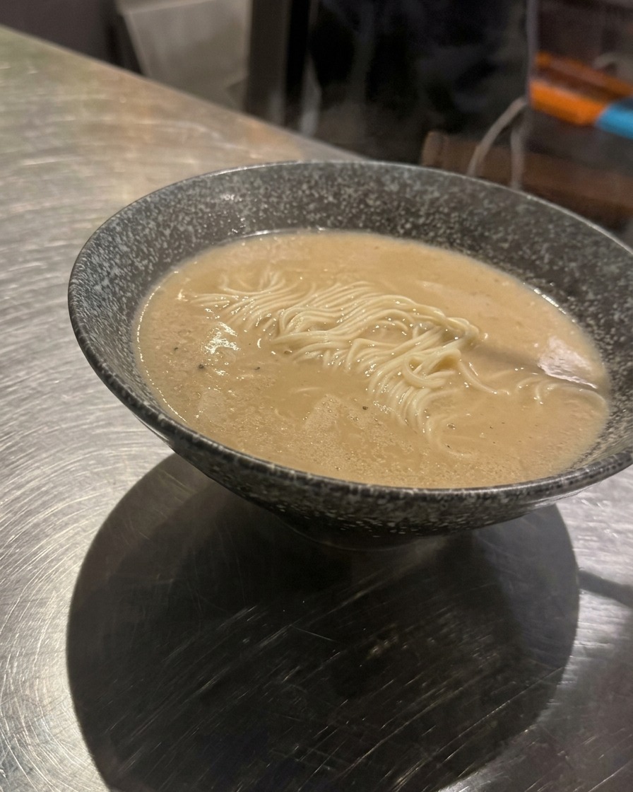 그릇에 담긴 라멘 면 중앙에 다진 고기 고명을 올리는 모습.