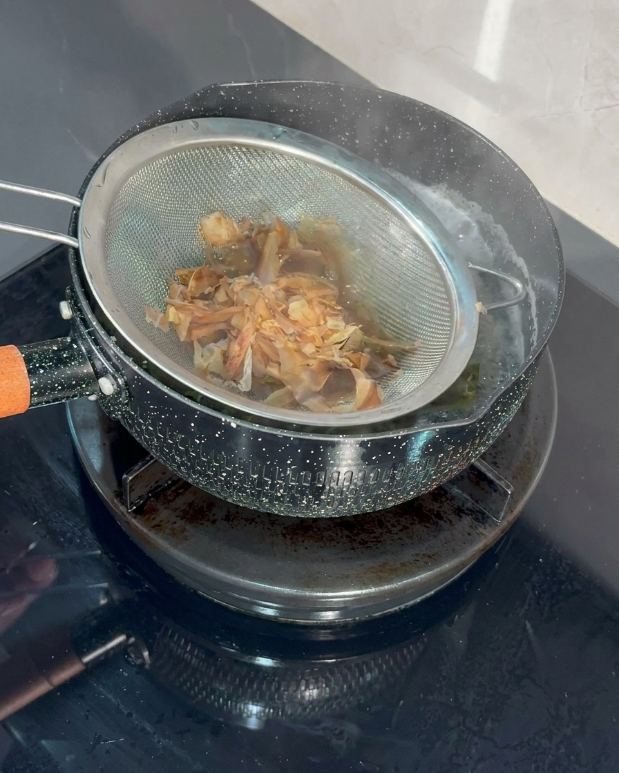 채망에 가쓰오부시를 담아 끓는 국물에 담그는 모습.