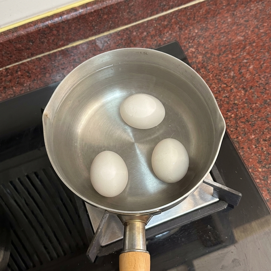 따뜻한 물이 담긴 냄비 바닥에 흰 달걀 2개가 얌전하게 가라앉아 있는 모습.
