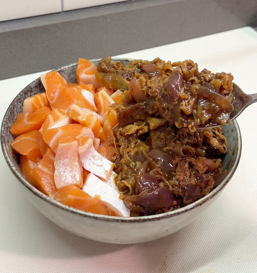 연어가 담긴 그릇의 나머지 반쪽에 윤기 나는 소고기 볶음을 푸짐하게 담는 모습.