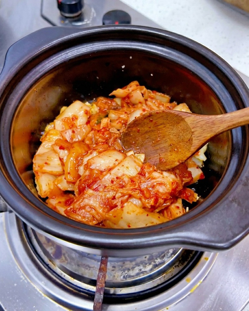 다진 마늘을 볶던 냄비에 먹기 좋게 썬 배추김치를 넣는 모습