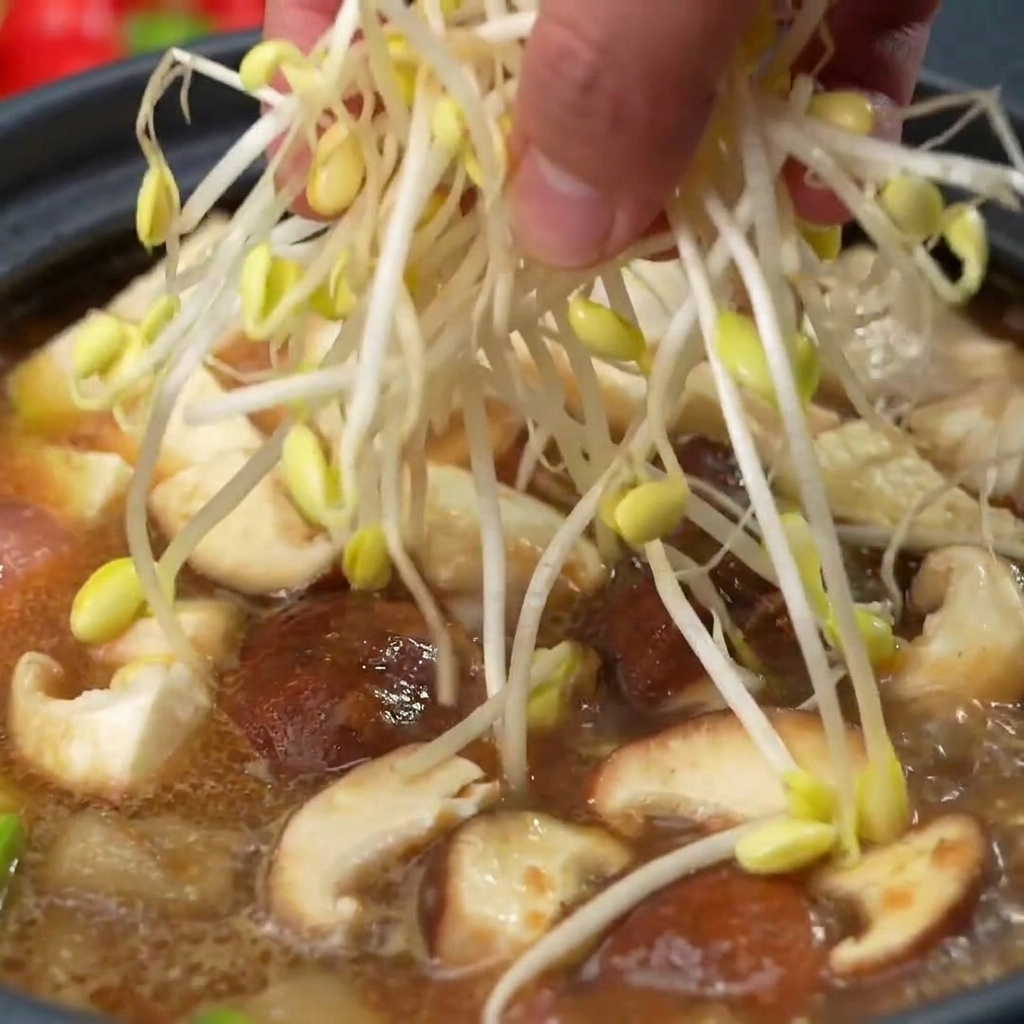 버섯과 두부가 담긴 찌개 냄비 맨 위에 싱싱하고 깨끗한 콩나물 한 줌을 수북하게 올리는 모습