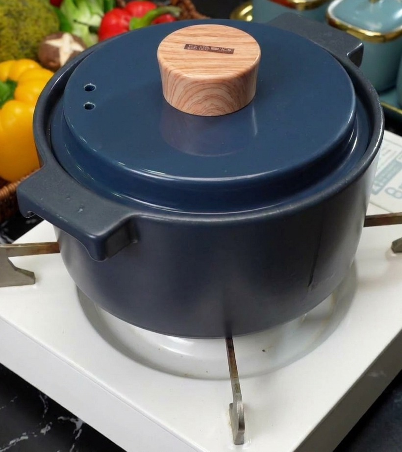 휴대용 가스버너 위에서 깔끔한 뚜껑이 닫힌 채 은근하게 끓고 있는 찌개 냄비의 전경