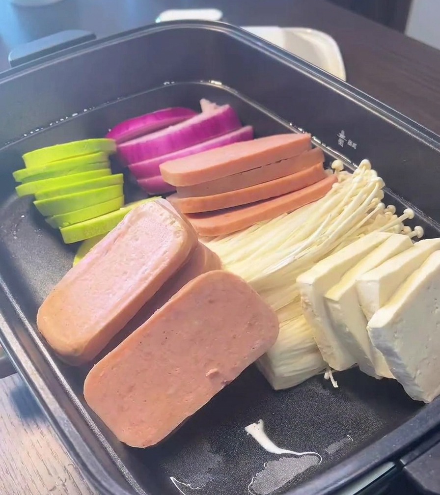 적양파, 애호박, 통조림 햄, 팽이버섯, 두부가 구역을 나누어 깔끔하게 정돈되어 담긴 검은색 전골 냄비