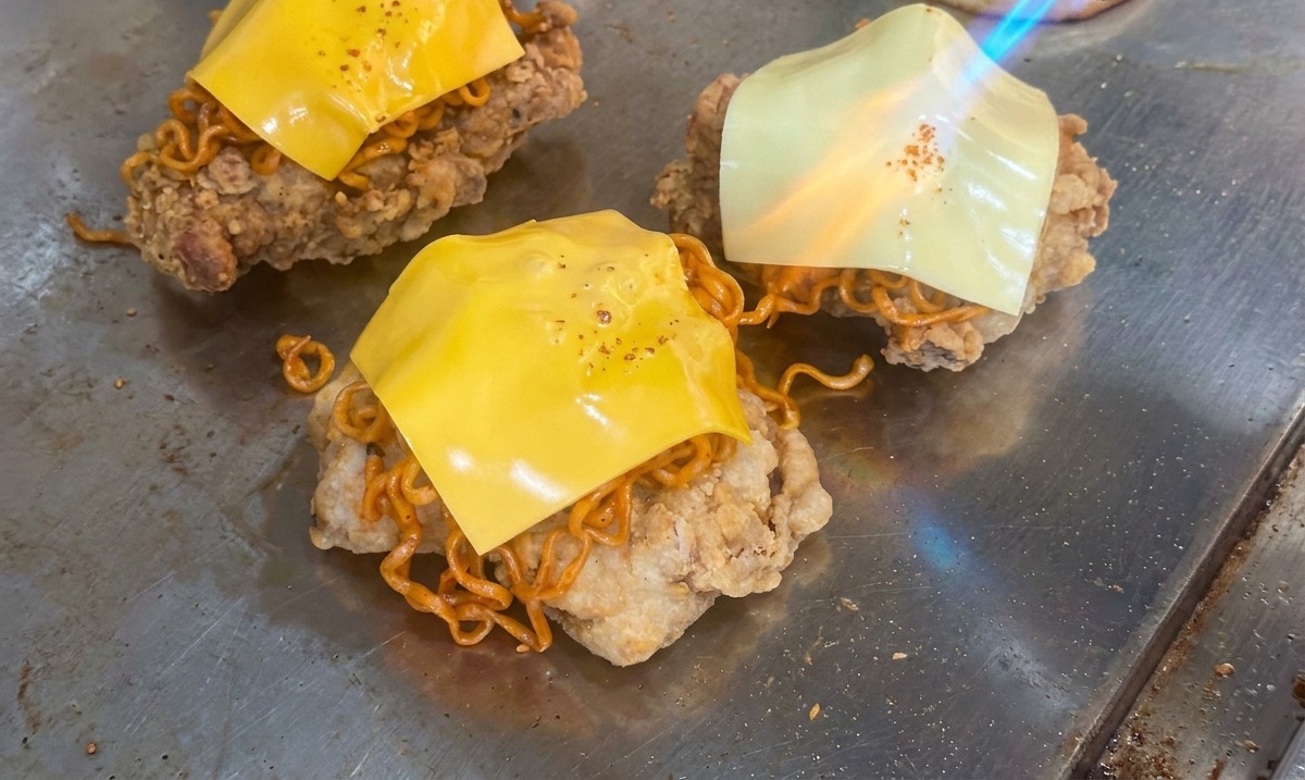 치킨 패티와 면 위에 올린 치즈를 토치 불꽃으로 녹이는 모습