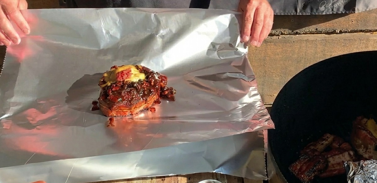 치즈가 알맞게 녹아내린 완성된 BBQ 립 컵이 포장되기 직전 넓은 알루미늄 호일 시트 위에 놓여 있는 모습.