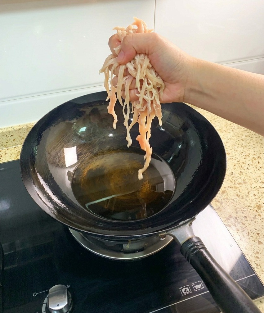 달구어진 웍의 뜨겁고 투명한 식용유에 잘게 썬 생 닭가슴살을 넣는 모습.