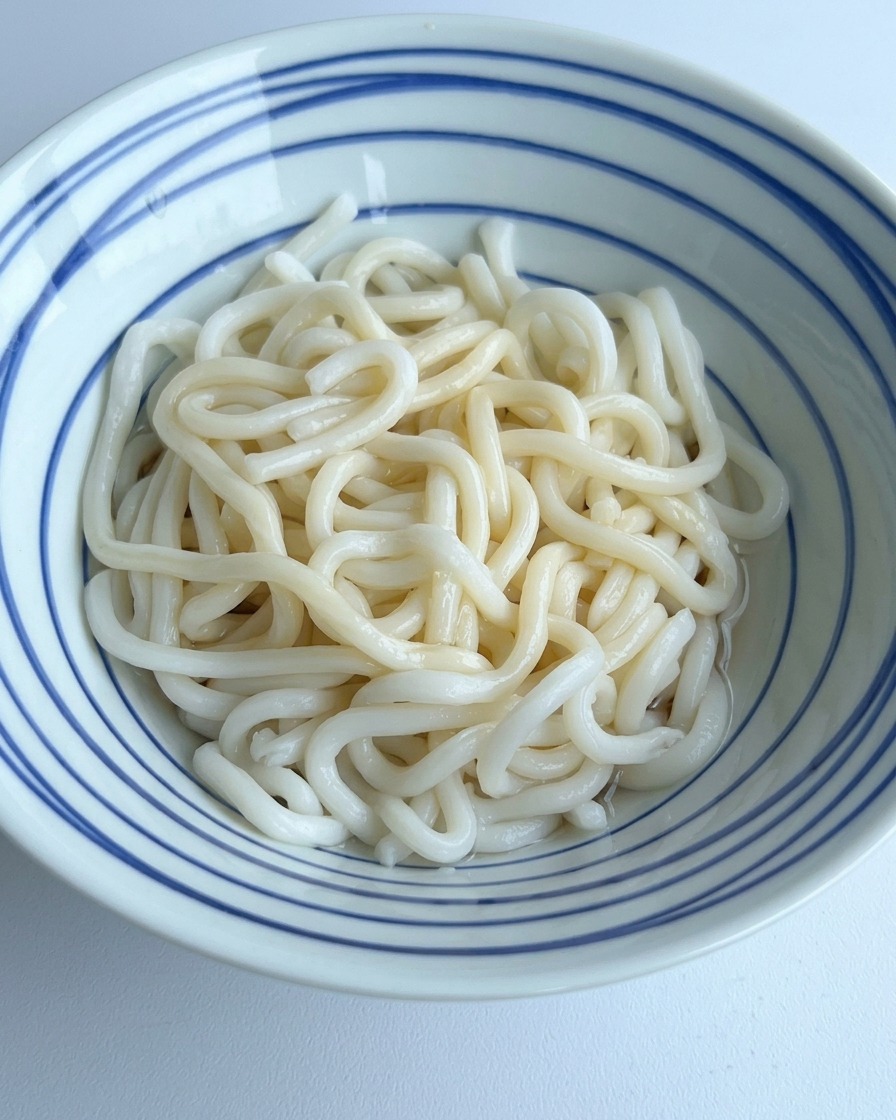 우동면이 담긴 그릇에 맑은 물을 부어 바닥의 진한 양념과 섞이게 하는 모습