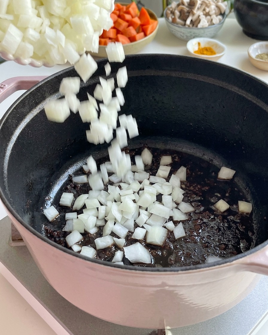 주물 냄비에 다진 흰 양파를 넣고 볶는 모습.