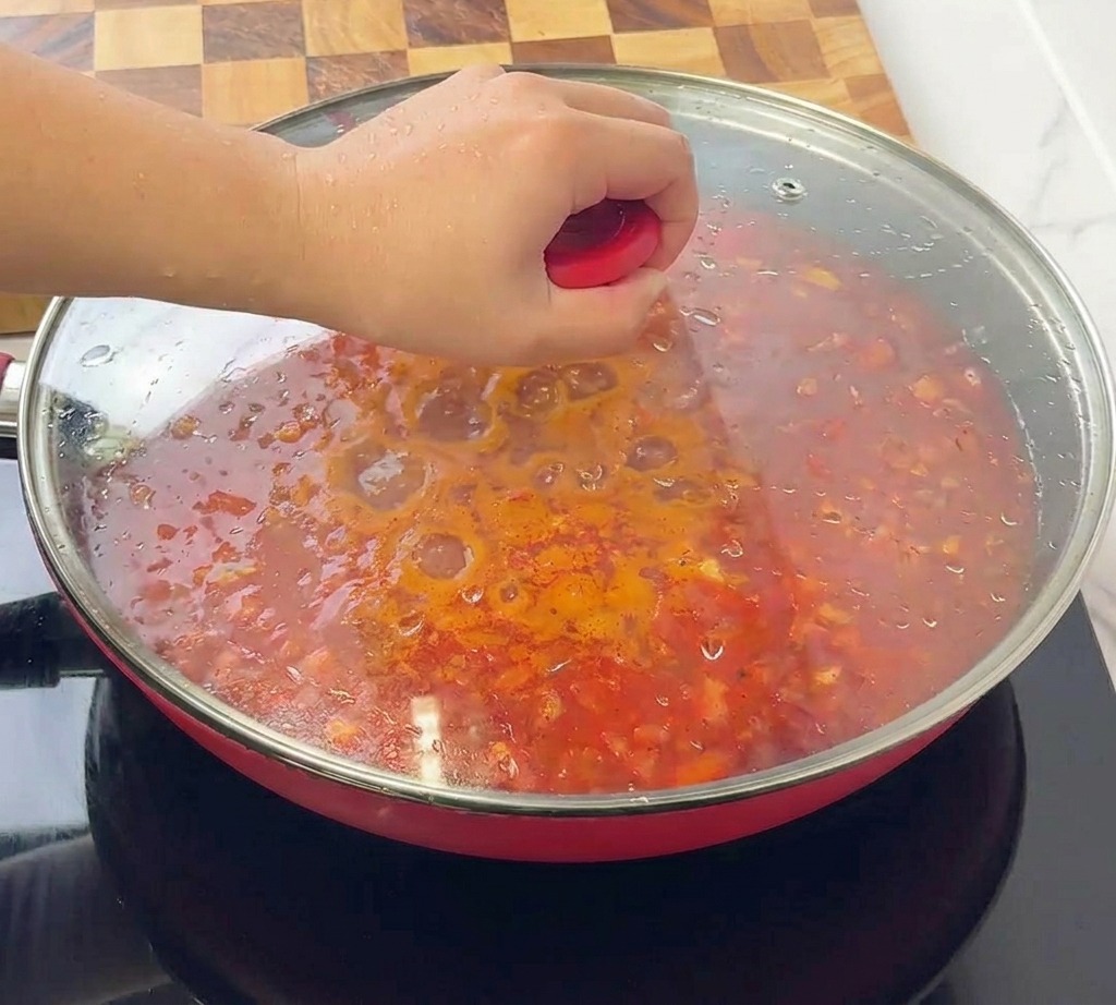 볼로네제 소스가 가득 담긴 빨간 스킬렛 위에 투명한 유리 뚜껑을 덮는 모습.