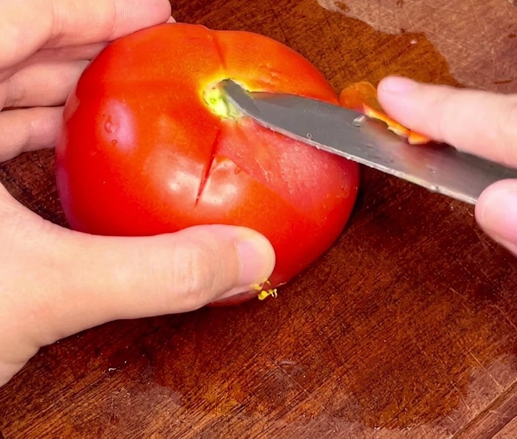 뜨거운 물에 데친 토마토의 껍질을 과도로 조심스럽게 벗겨내는 손