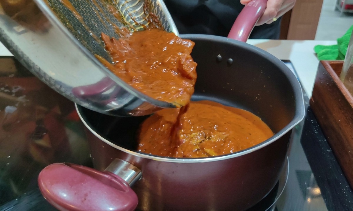 물기를 뺀 리카토니가 담긴 냄비에 프라이팬에 있던 붉은 아마트리치아나 소스를 조심스럽게 붓는 모습