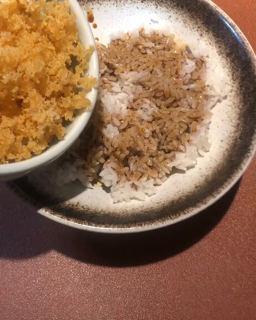 소스가 뿌려진 밥 위에 텐카스를 뿌리는 모습.
