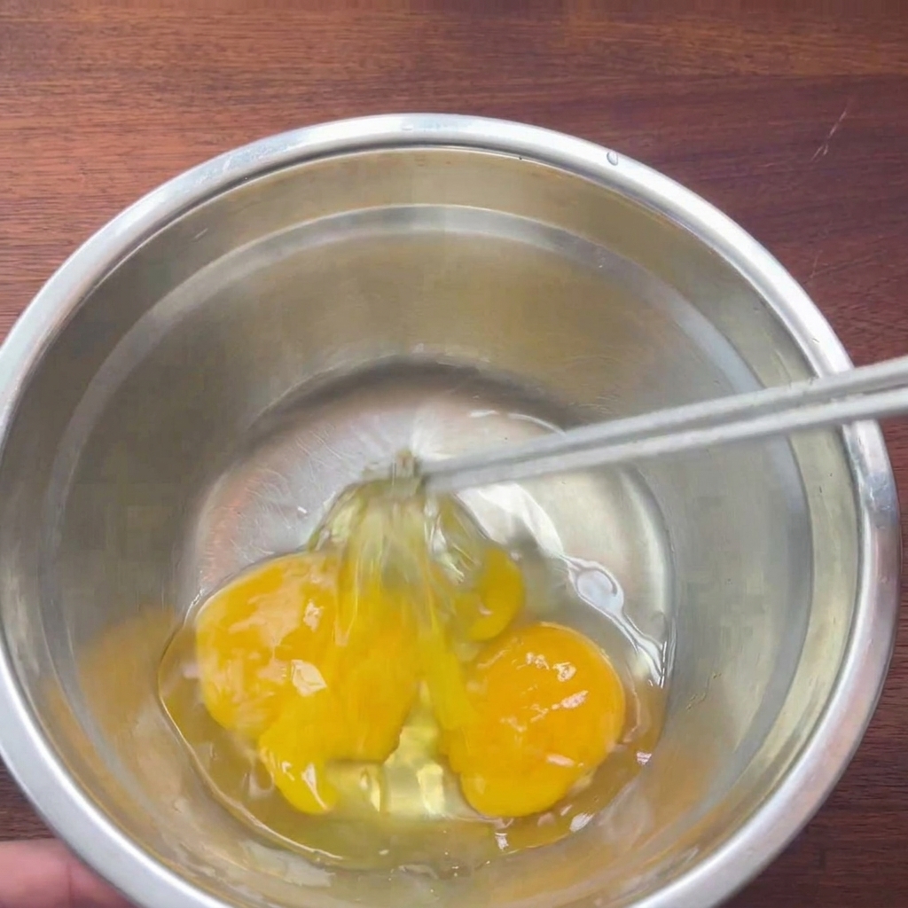 그릇에 담긴 달걀을 젓가락으로 가볍게 풀어주는 모습.