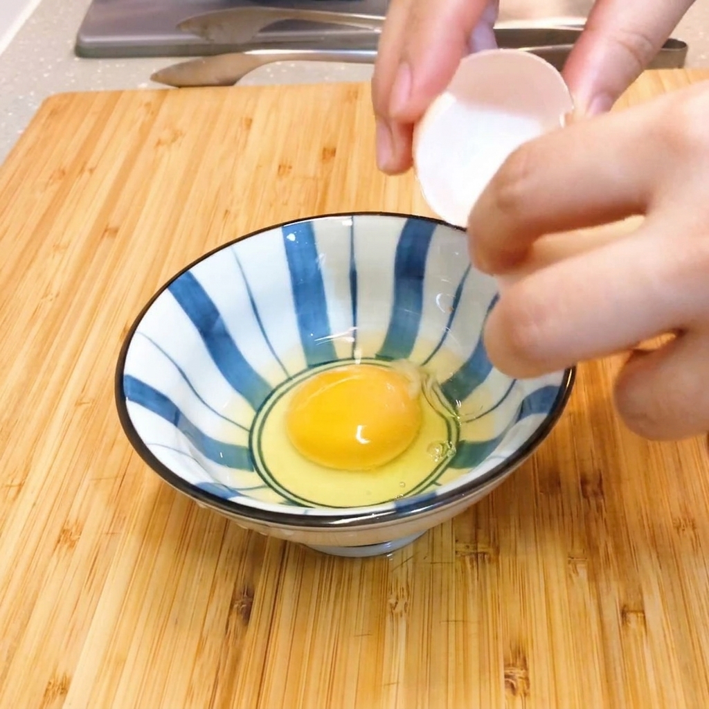 줄무늬 그릇에서 젓가락으로 달걀을 가볍게 푸는 모습.