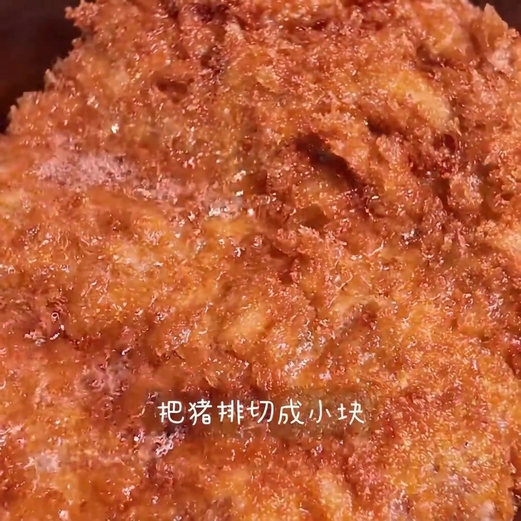 나무 도마 위에서 황금빛으로 바삭하게 튀겨진 돈까스를 길쭉하게 써는 모습.
