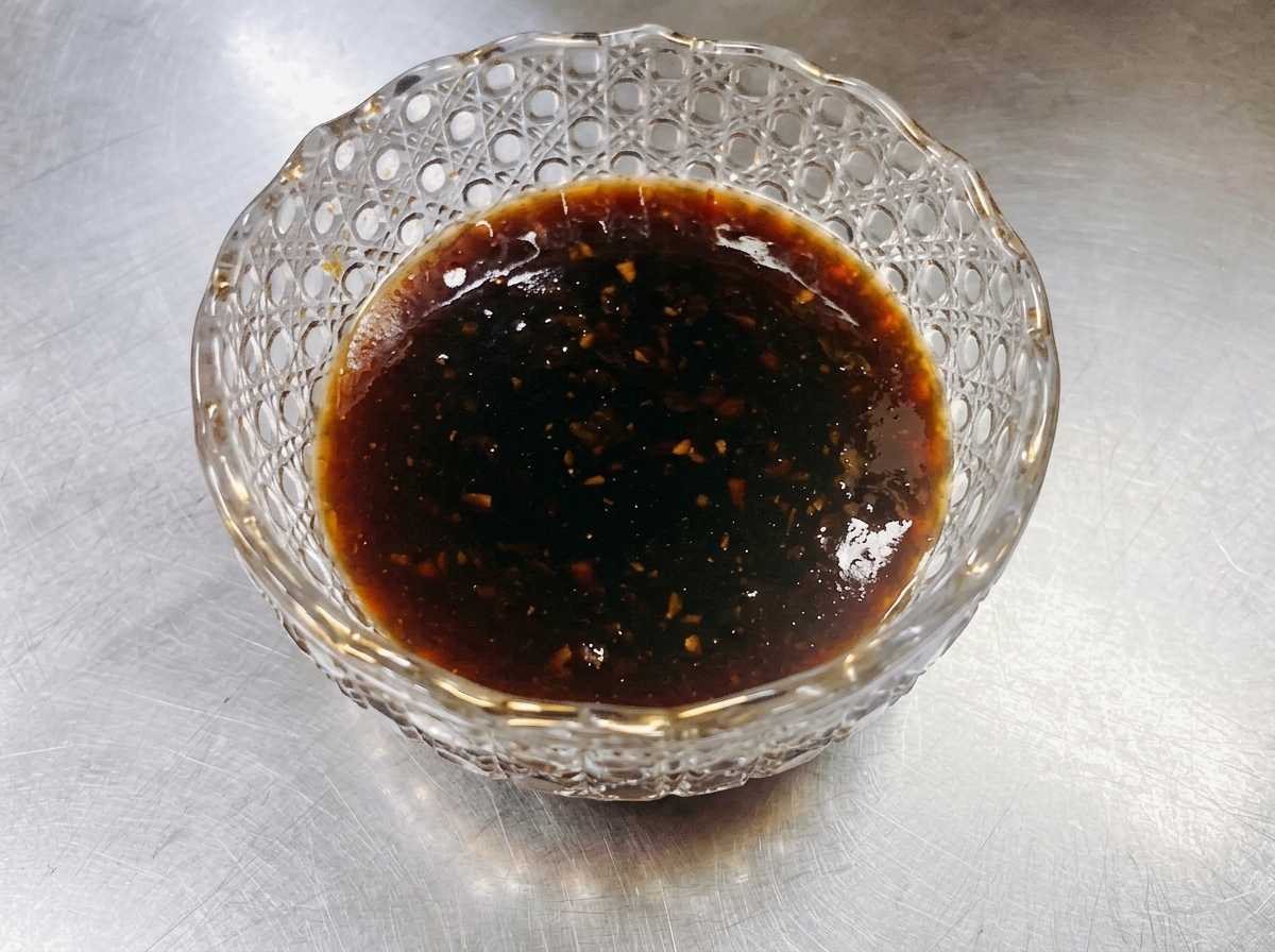 팬에서 조리 중인 소고기 위에 어둡고 윤기 나는 데리야끼 소스를 부어 진한 광택을 내는 모습.