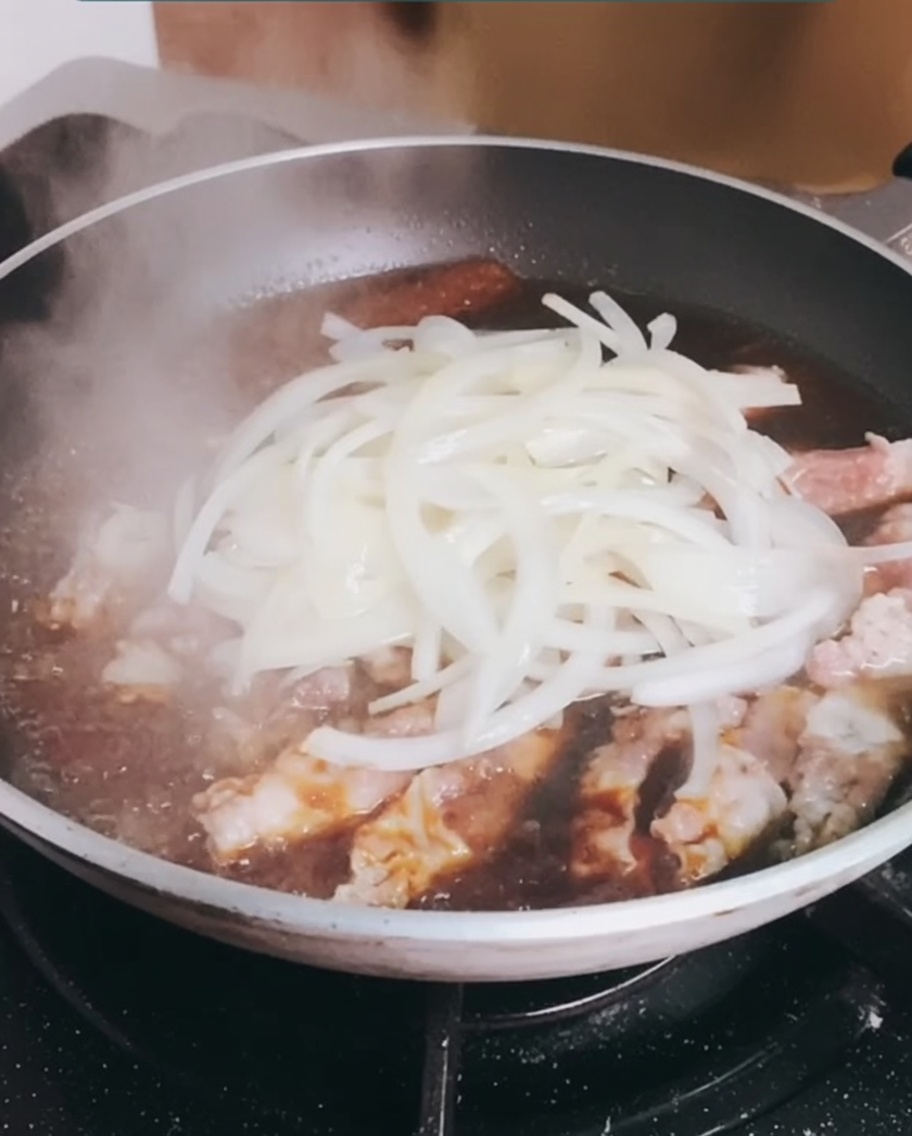 미리 볶아둔 양파를 끓고 있는 소고기 팬에 다시 넣는 모습.