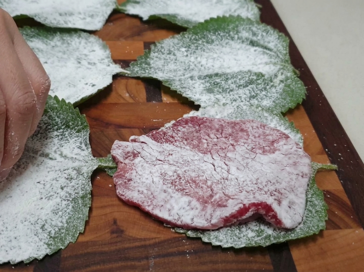 가루를 묻힌 깻잎 중앙에 소고기 한 점을 가지런히 올리는 모습.
