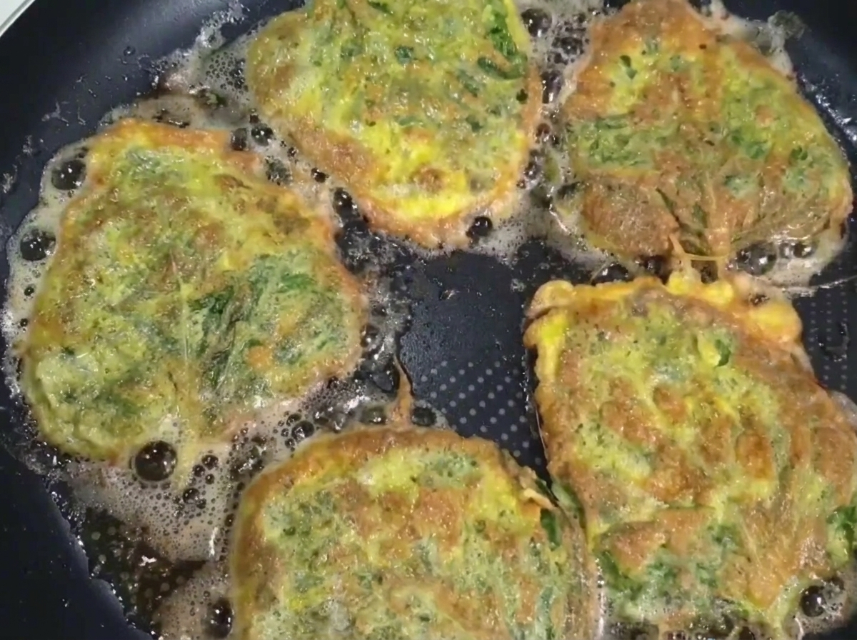 팬에서 노릇하게 구워진 깻잎전을 뒤집개와 젓가락으로 꺼내는 모습.