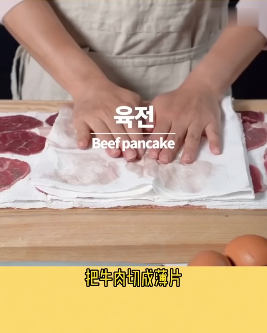 키친타월 위에 놓인 얇은 소고기 슬라이스에 참기름을 살짝 바르는 모습.