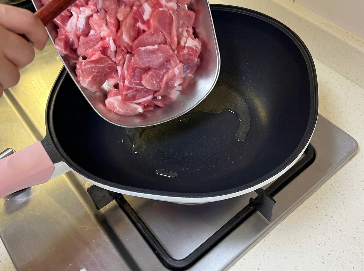 달궈진 팬에 얇은 돼지고기를 넣고 볶는 모습.