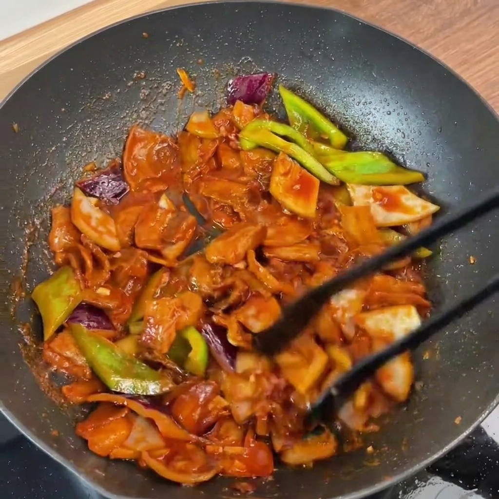 완성된 제육볶음을 집게로 섞는 모습.