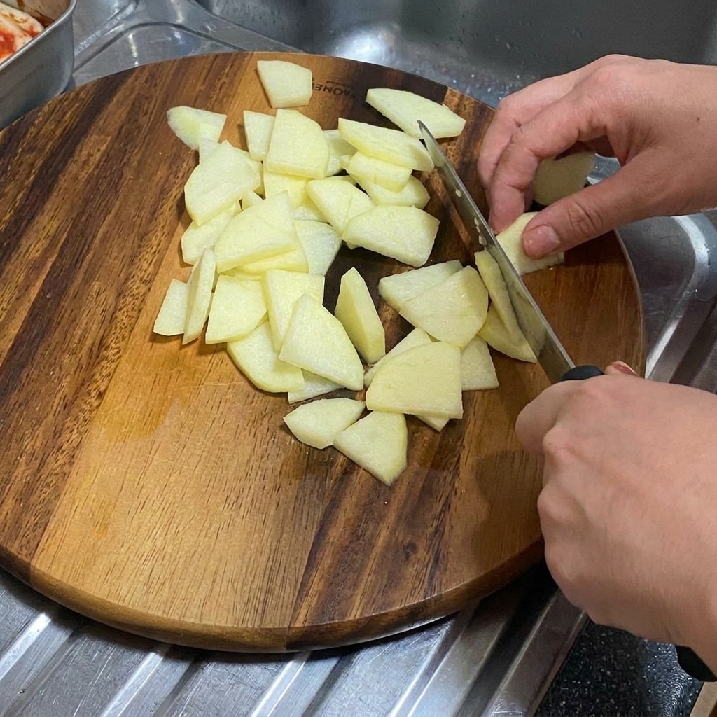 나무 도마 위에서 양파를 두껍게 썰고 있는 모습.