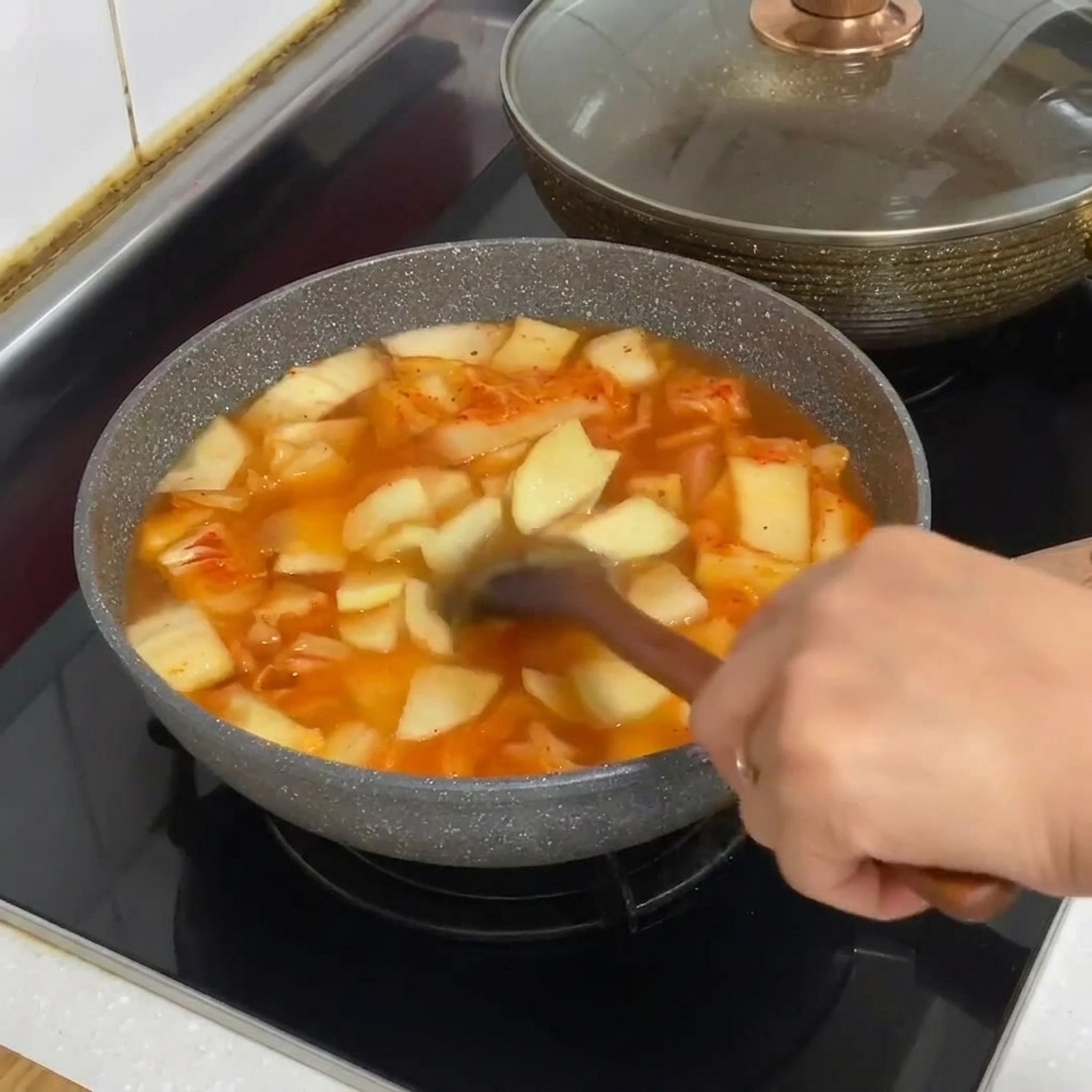 보글보글 끓는 김치찌개 냄비에 당면을 넣는 모습.