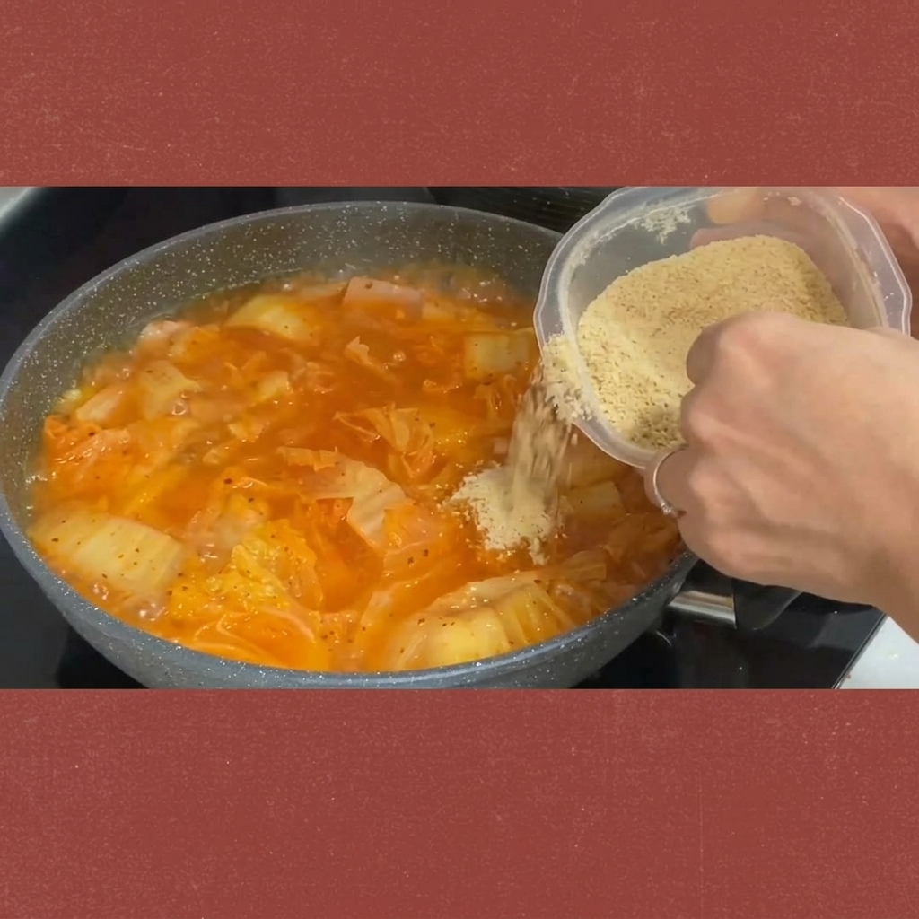 끓고 있는 김치찌개에 설탕을 뿌려 넣는 모습.