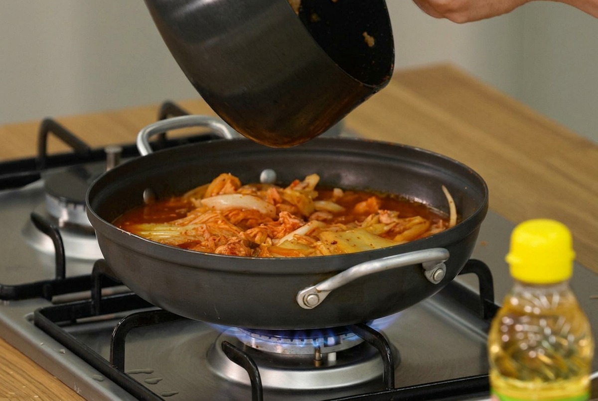 끓는 김치찌개 위에 두부와 대파를 올리는 모습.