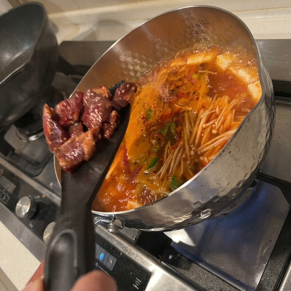 재료가 가득한 냄비에 밑간한 소고기를 넣어 익히는 모습.