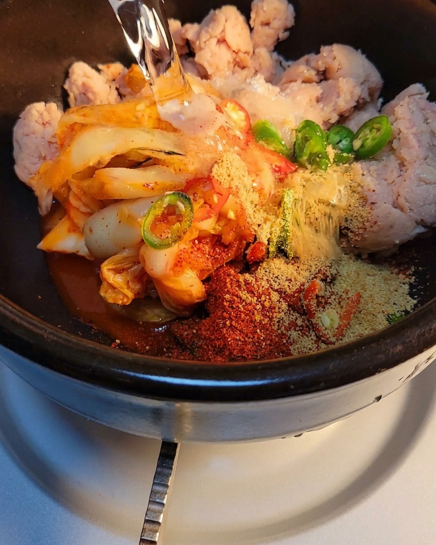 양념된 재료가 담긴 돌솥에 물을 붓고 가스레인지에 올린 모습.