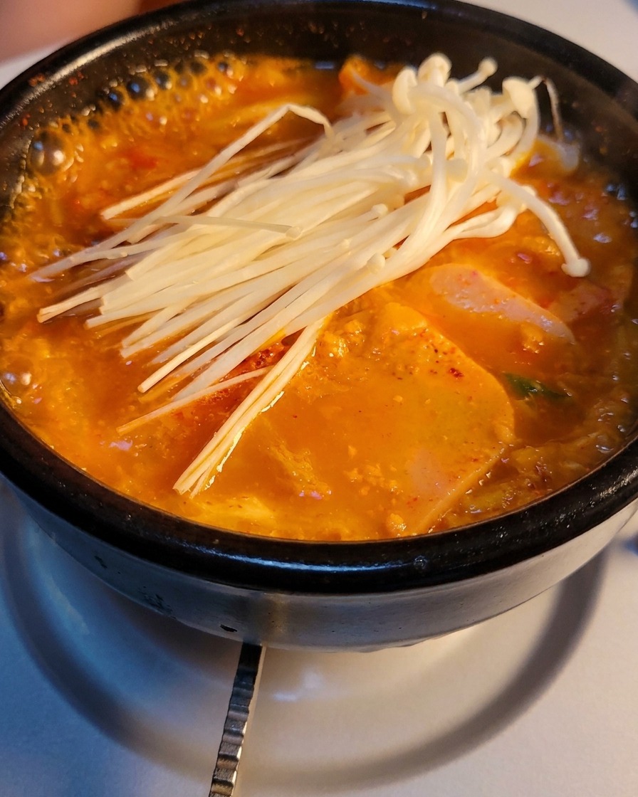 보글보글 끓는 찌개 위에 신선한 팽이버섯과 대파를 듬뿍 올린 돌솥.