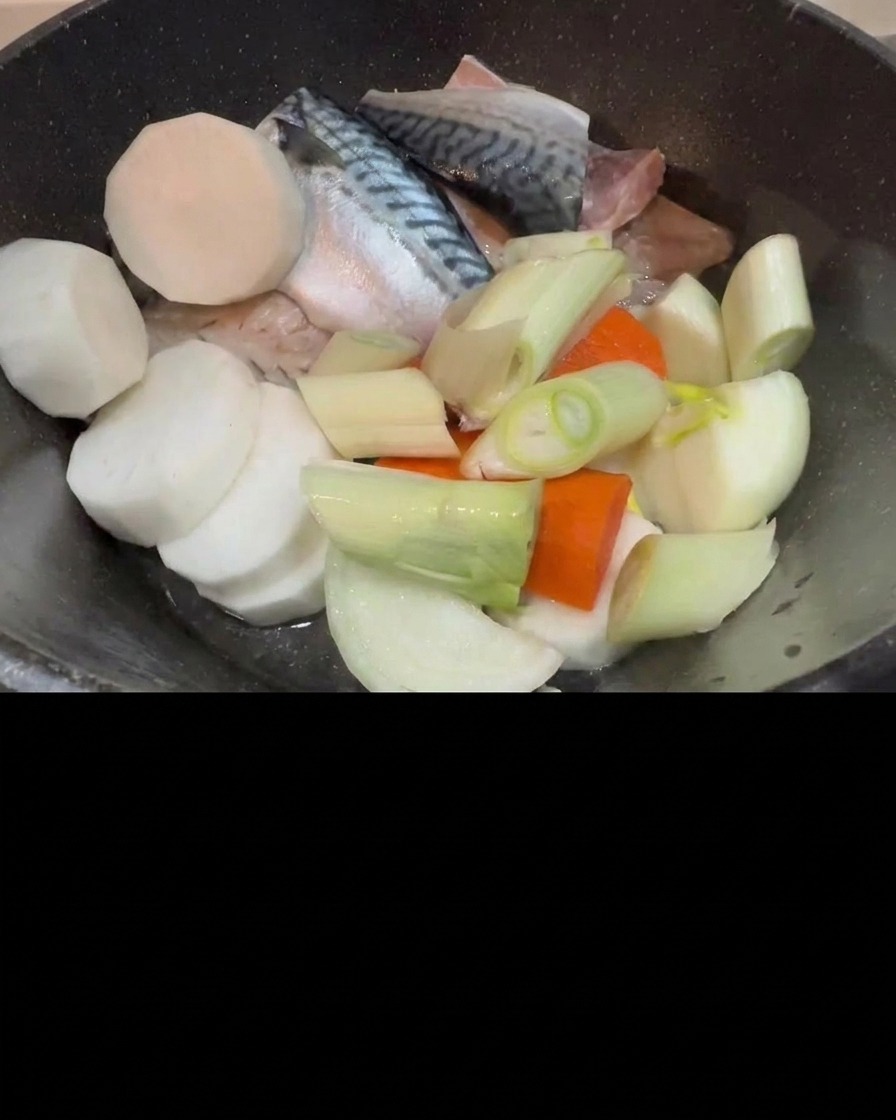고등어, 무, 파가 담긴 냄비에 김치를 넉넉히 얹는 모습.
