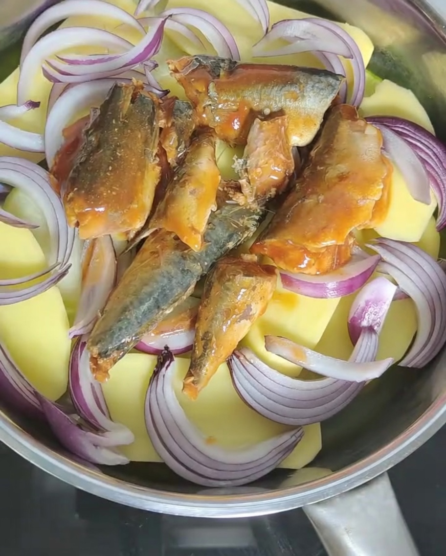 통조림 안의 토마토 소스를 냄비 속 재료 위로 붓는 모습.