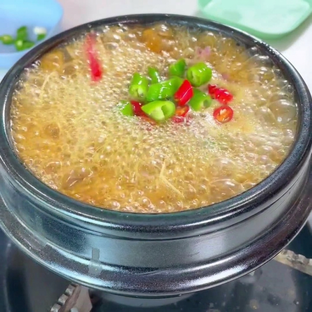 찌개 위에 다진 고추와 대파를 고명으로 올리는 모습.