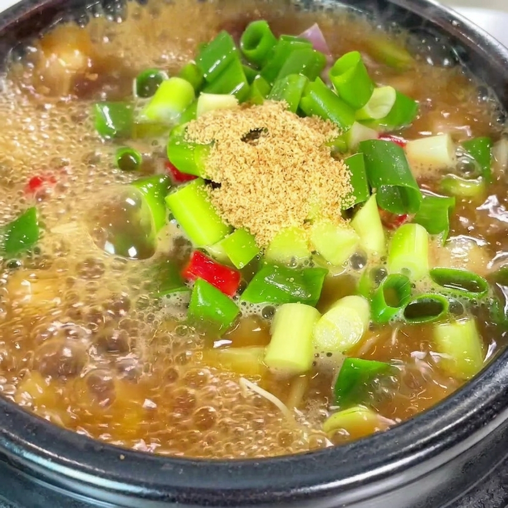 끓고 있는 된장찌개에 고춧가루를 더하는 모습.