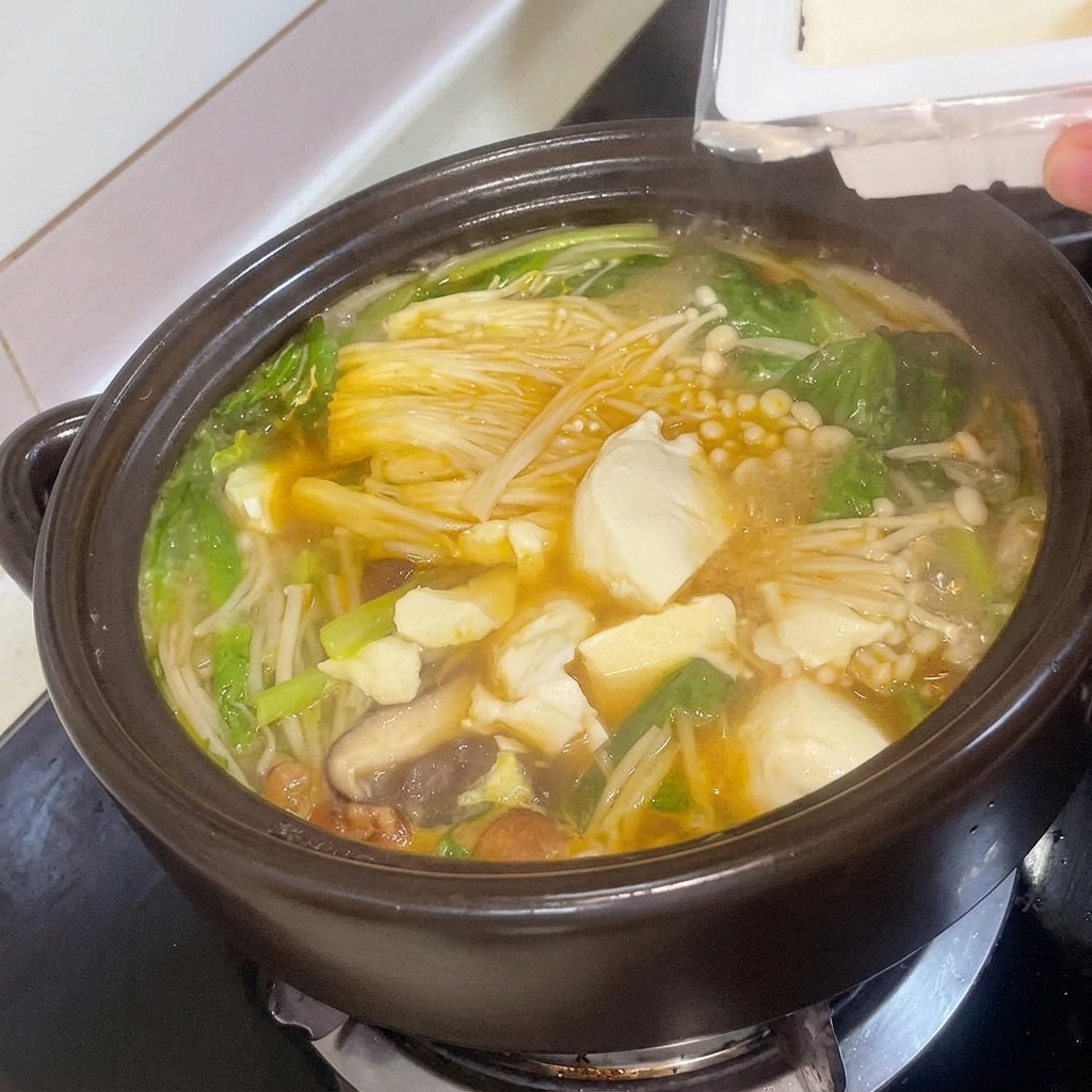 끓고 있는 된장찌개에 두부를 넣는 모습.