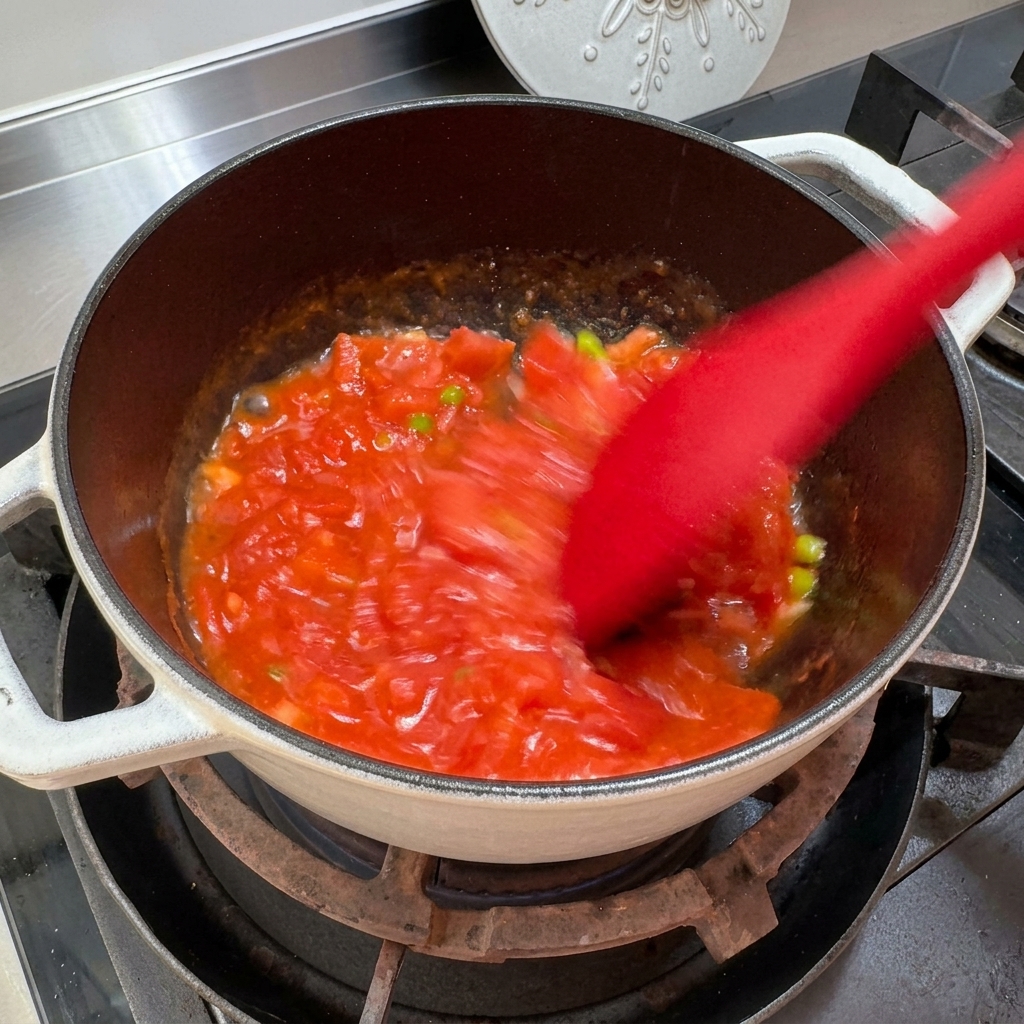 토마토를 으깨며 소스처럼 볶는 모습.