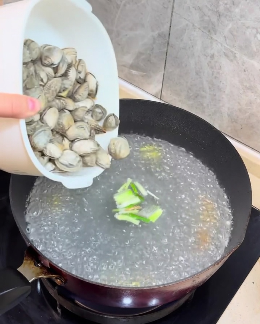 팔팔 끓는 육수에 신선한 바지락과 깍둑썰기한 두부를 넣는 모습.