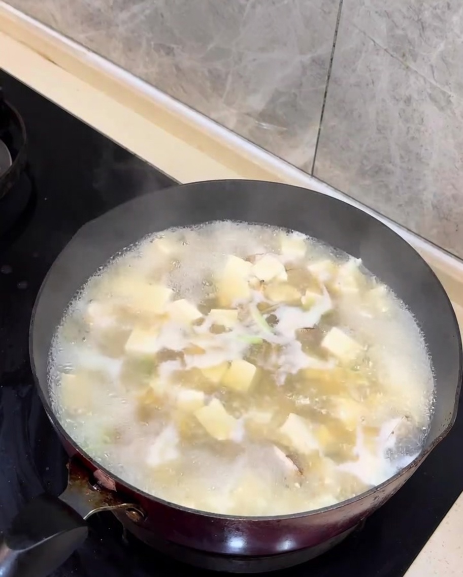 완성된 바지락 두부국 위에 잘게 썬 쪽파를 올리는 모습.