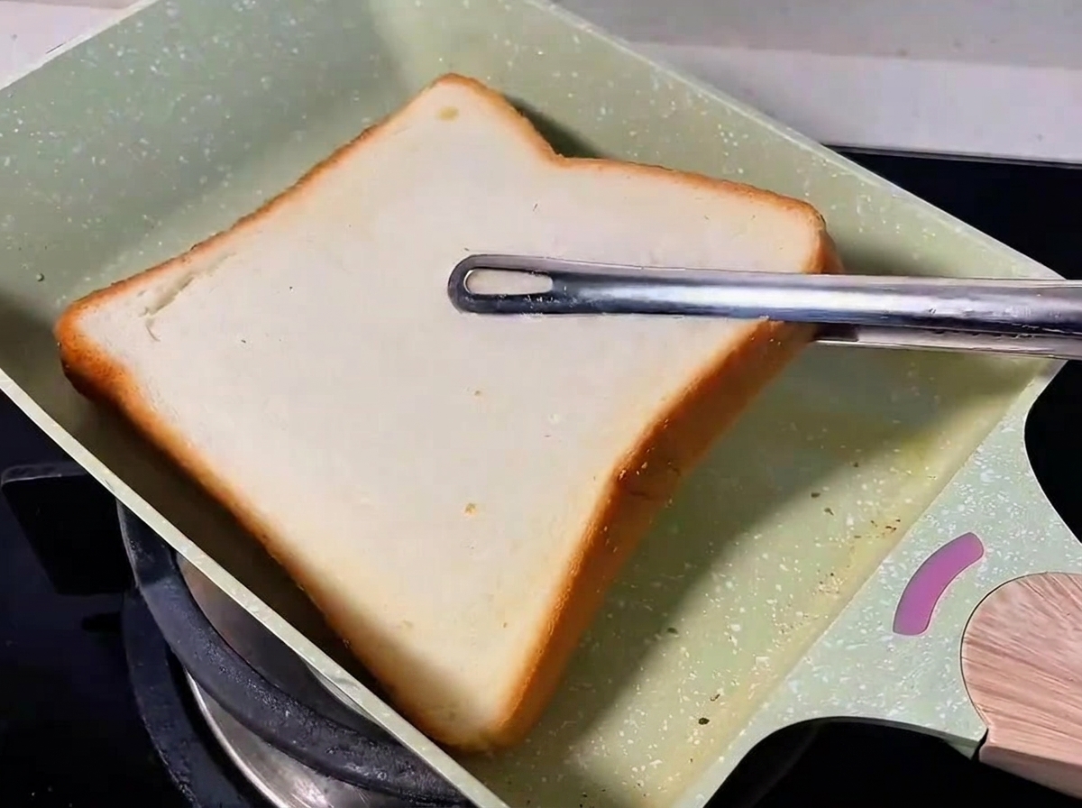 팬에서 노릇하게 굽히고 있는 식빵.