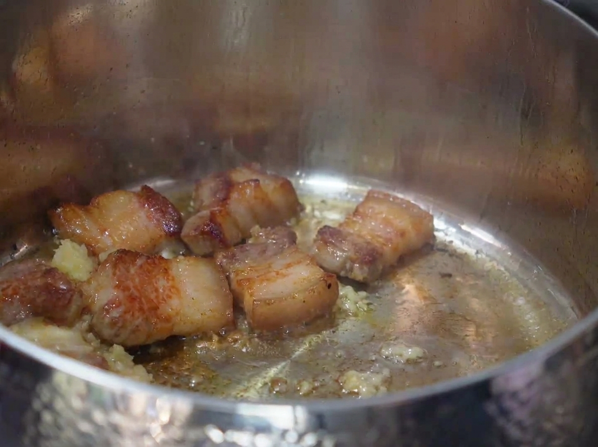 잘게 썬 김치를 볶아진 고기, 마늘과 함께 냄비에서 볶는 모습.