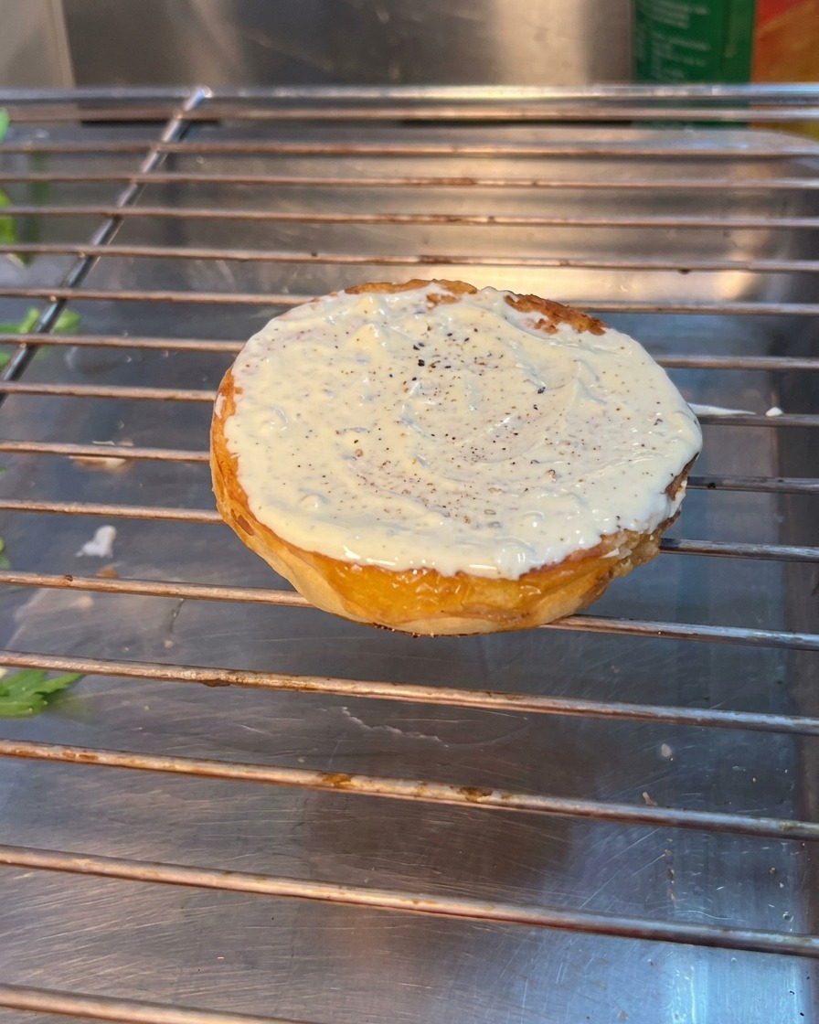 아랫면 번 위에 루꼴라, 토마토, 피클을 차례로 올린 모습.