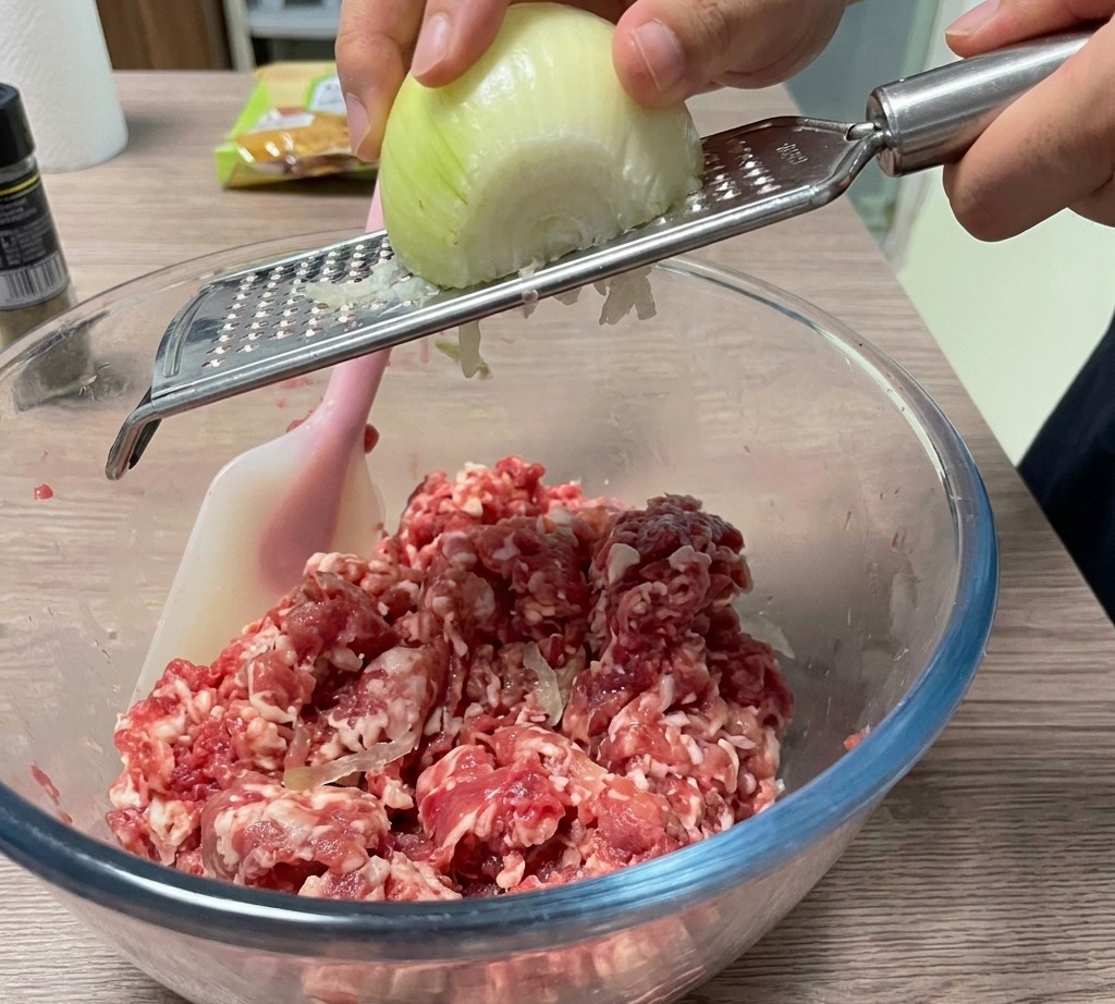 양파를 강판에 갈아 고기 볼에 넣는 모습.